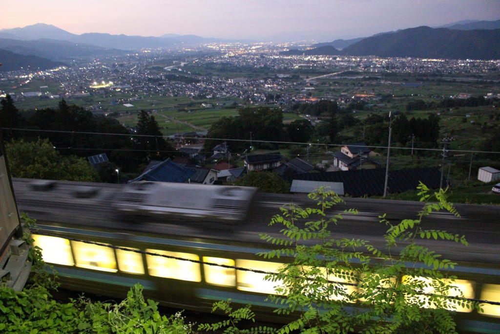 本線を通過する普通列車を夜景とともに