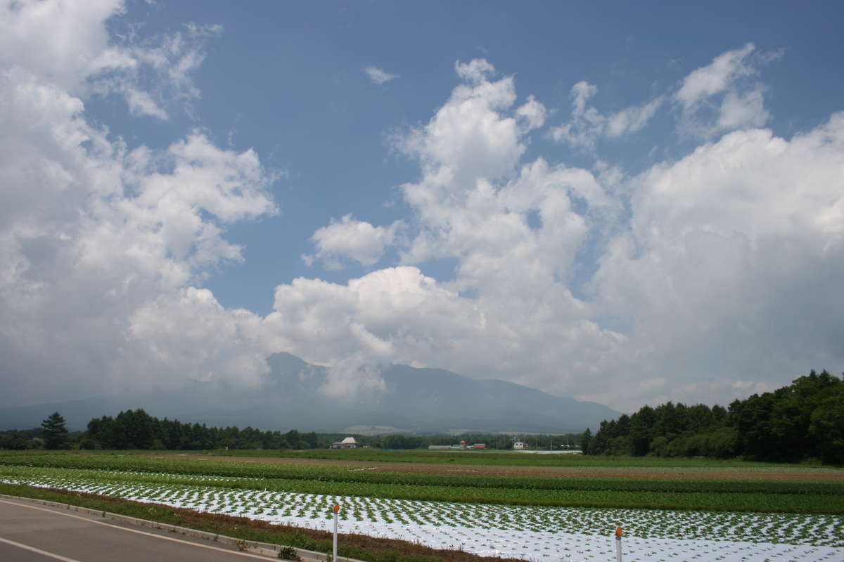 高原野菜の畑の向こうに八ヶ岳が見える野辺山駅付近の車窓