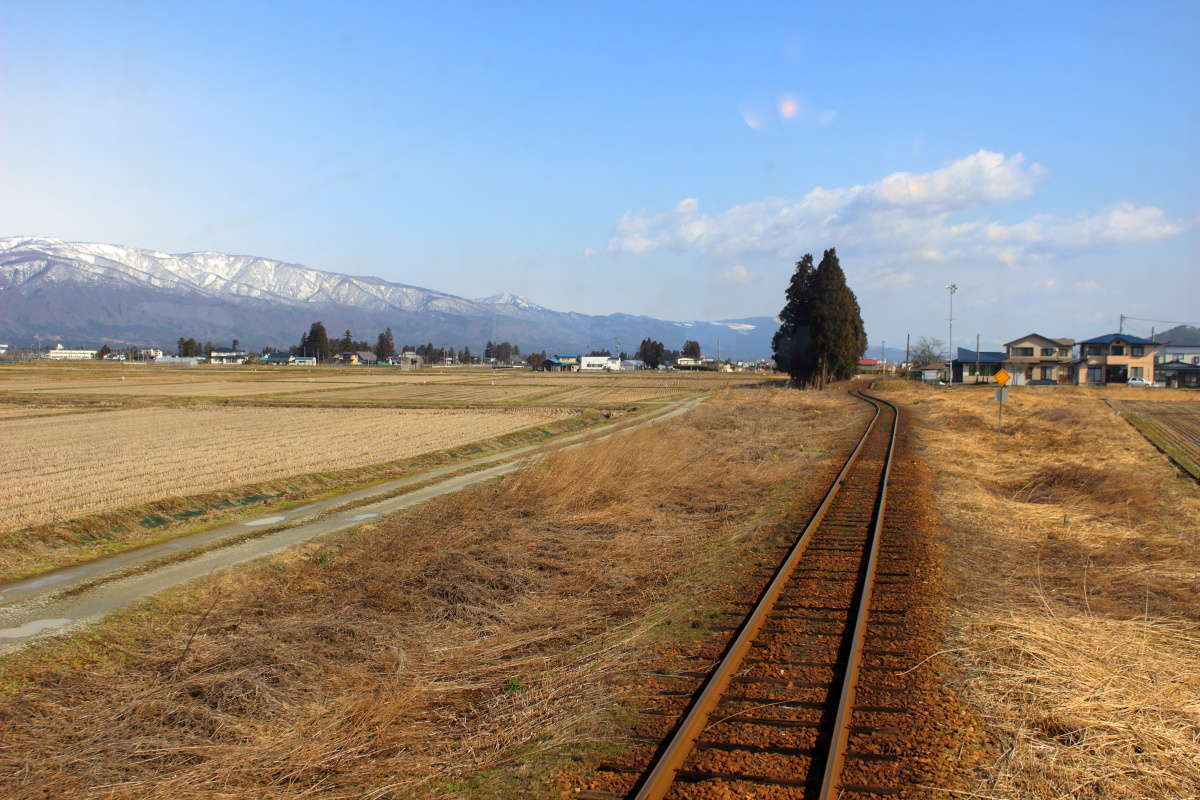 まだ冬の山々と春の息吹を感じる置賜盆地の車窓