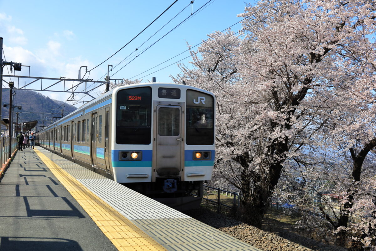 桜に囲まれた勝沼ぶどう郷駅に入線する甲府行きの普通列車