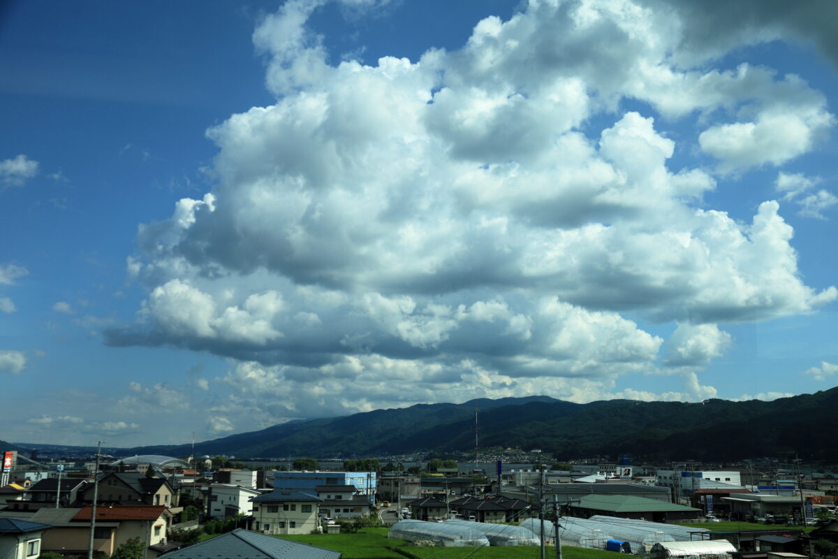 底が平らな雲が並ぶ岡谷駅付近の車窓