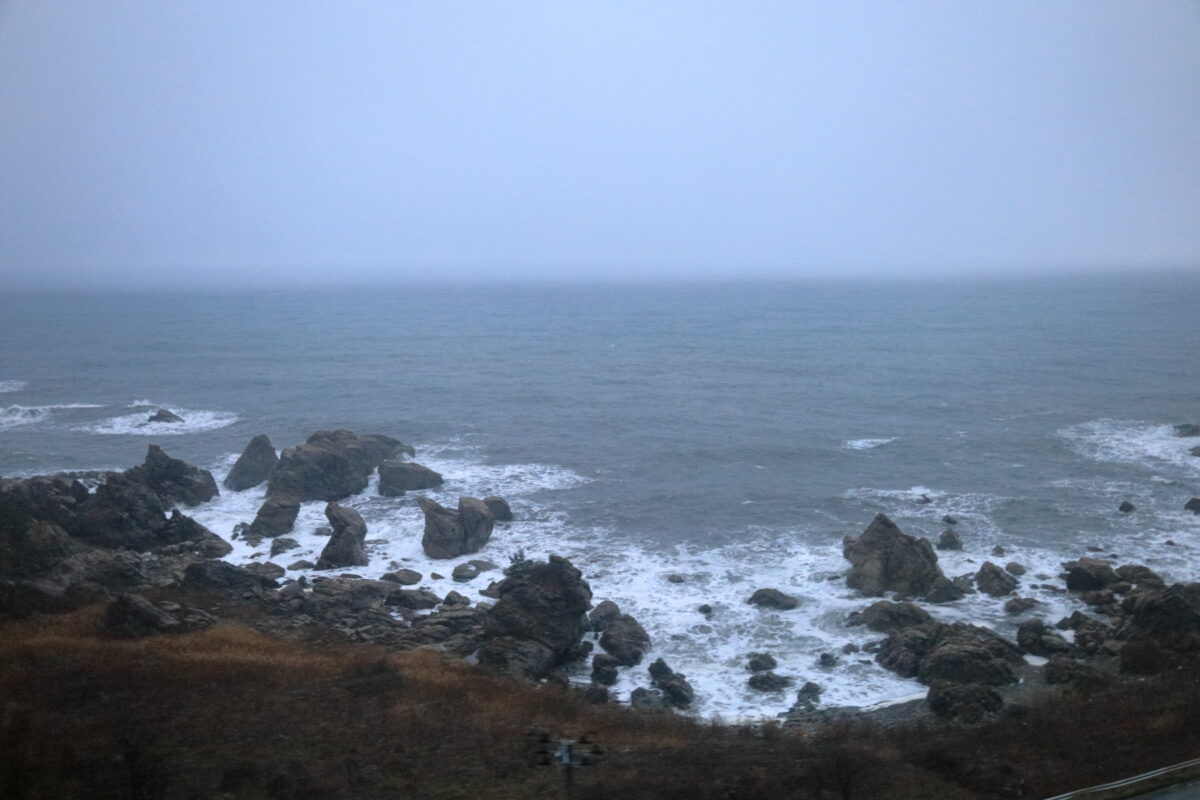 鈍色の空に白波が立つ冬の日本海（リゾートしらかみからの車窓）