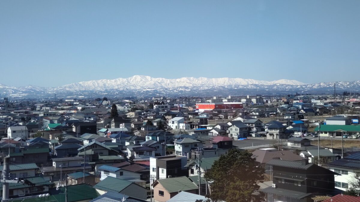 奥羽本線の普通列車から眺める赤湯の街並みと飯豊連峰